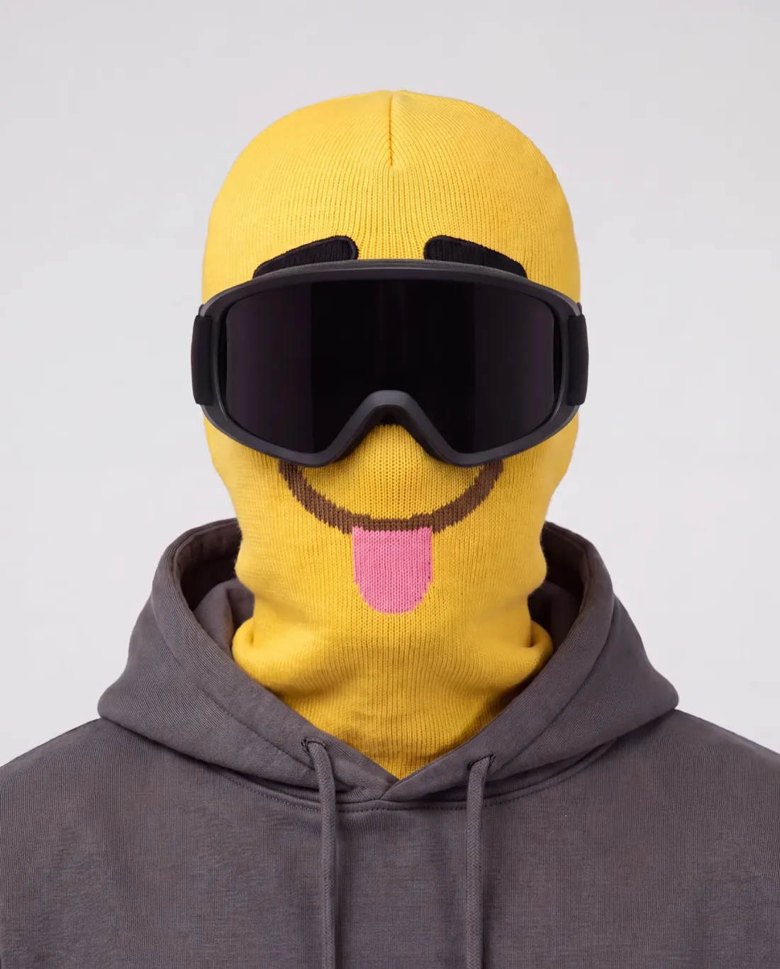 DERP yellow character ski mask, front studio view, tongue out, worn with black-lens ski goggles